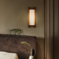Neyro wall light lit beside a wooden headboard in a bedroom