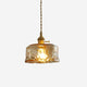 Cadro amber glass drum pendant light on a plain white background, wide rippled glass shade with brass lampholder