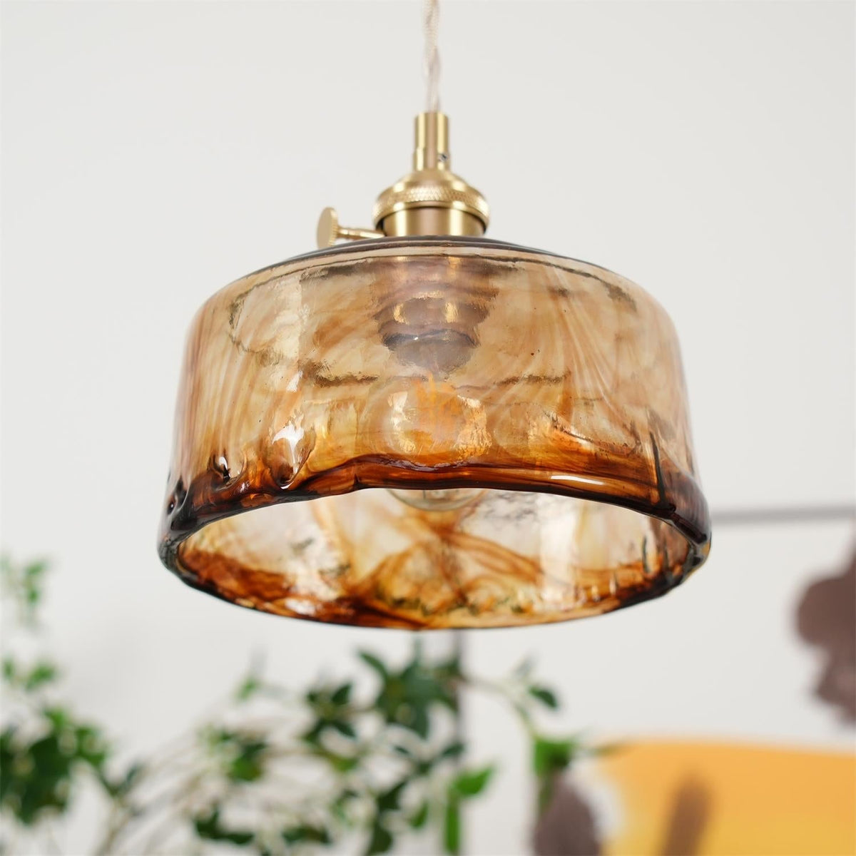 Close view of the Cadro pendant showing the rippled lower rim and amber tone of the glass shade