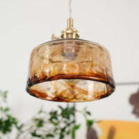 Close view of the Cadro pendant showing the rippled lower rim and amber tone of the glass shade