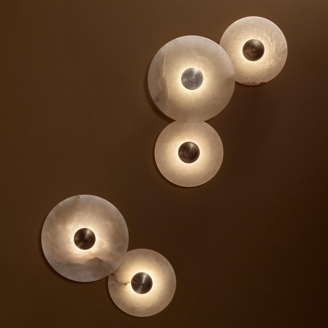 Corven alabaster disc wall sconces illuminated on dark wall