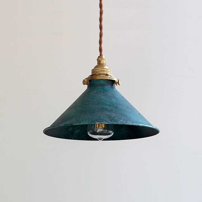 Pepa pendant light lit with a warm bulb showing the teal verdigris cone shade and twisted brown flex