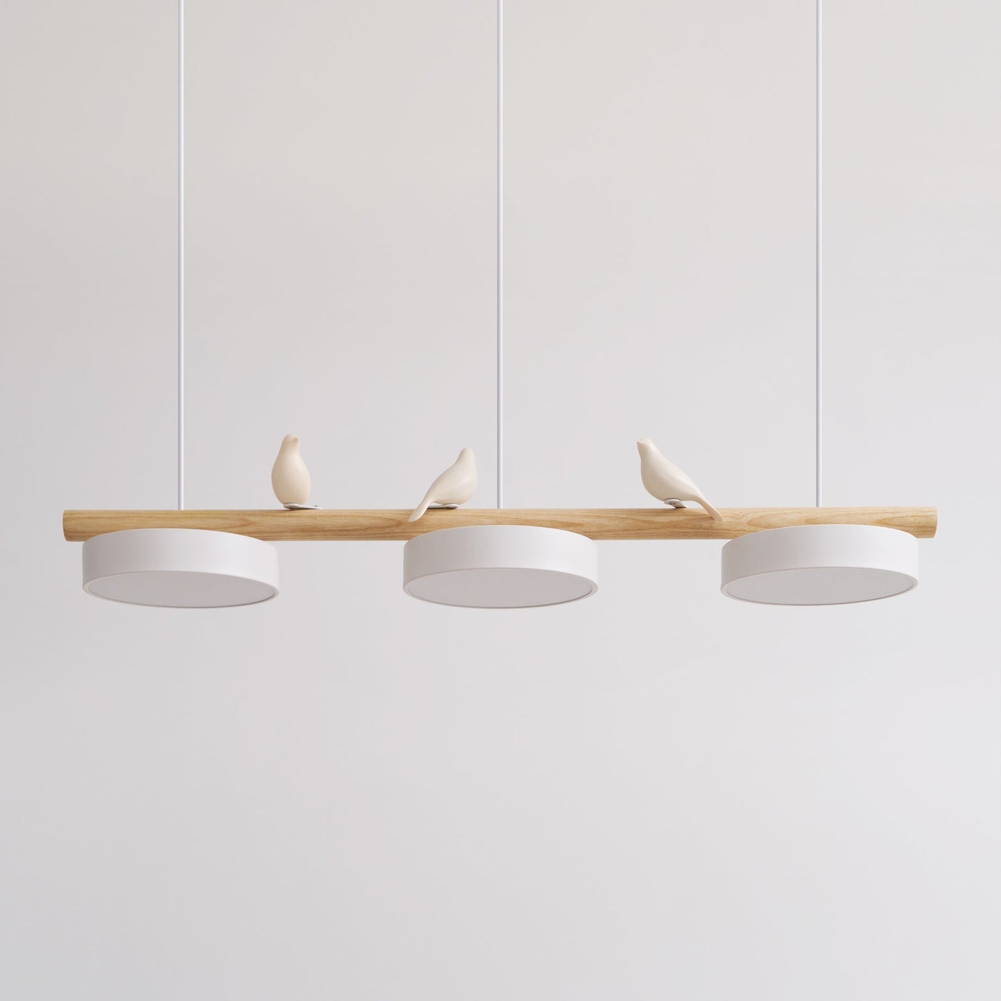 Clifo bird branch linear pendant light on a plain background, natural wood bar with three white disc shades and three cream ceramic birds