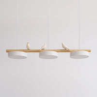 Clifo bird branch linear pendant light on a plain background, natural wood bar with three white disc shades and three cream ceramic birds