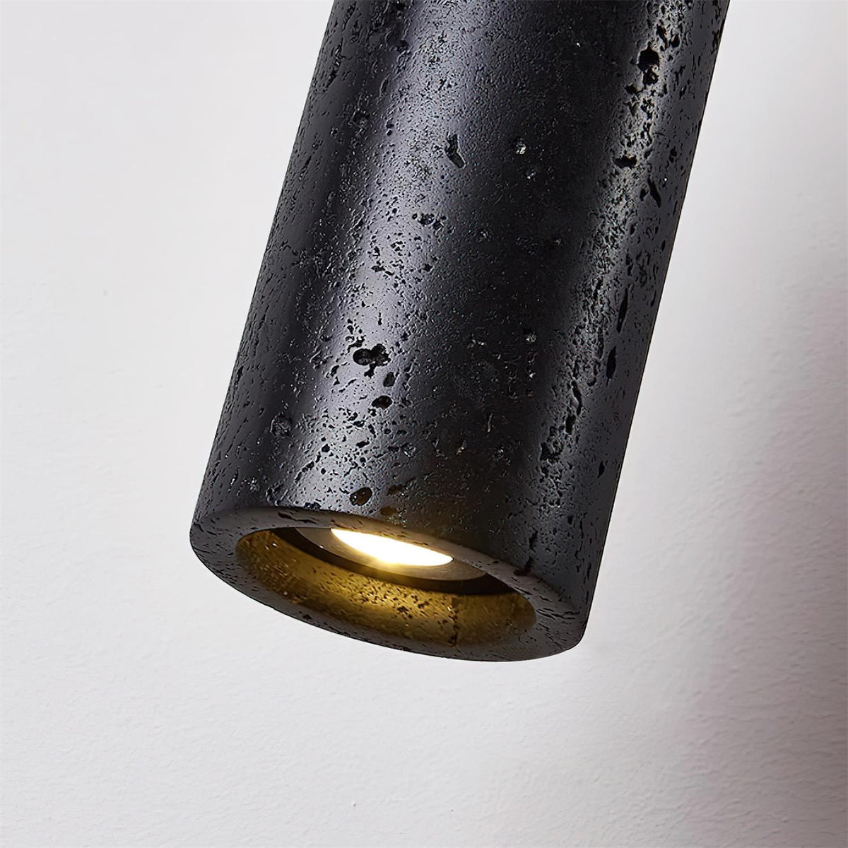 Detail of the pitted black travertine texture along the Basalo pendant shade