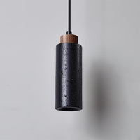 Basalo pendant lit, showing the warm downward beam from the open base of the stone tube