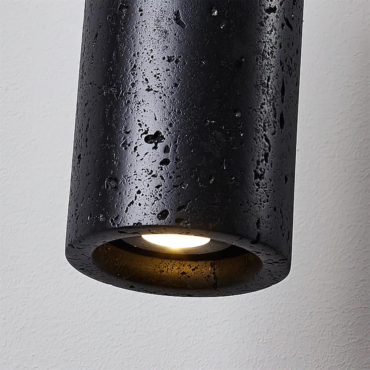 Close view of the Basalo travertine surface and the lit inner face of the cylinder