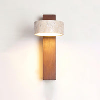 Nydo travertine wall light lit on a white wall with the stone drum set square to the walnut beam