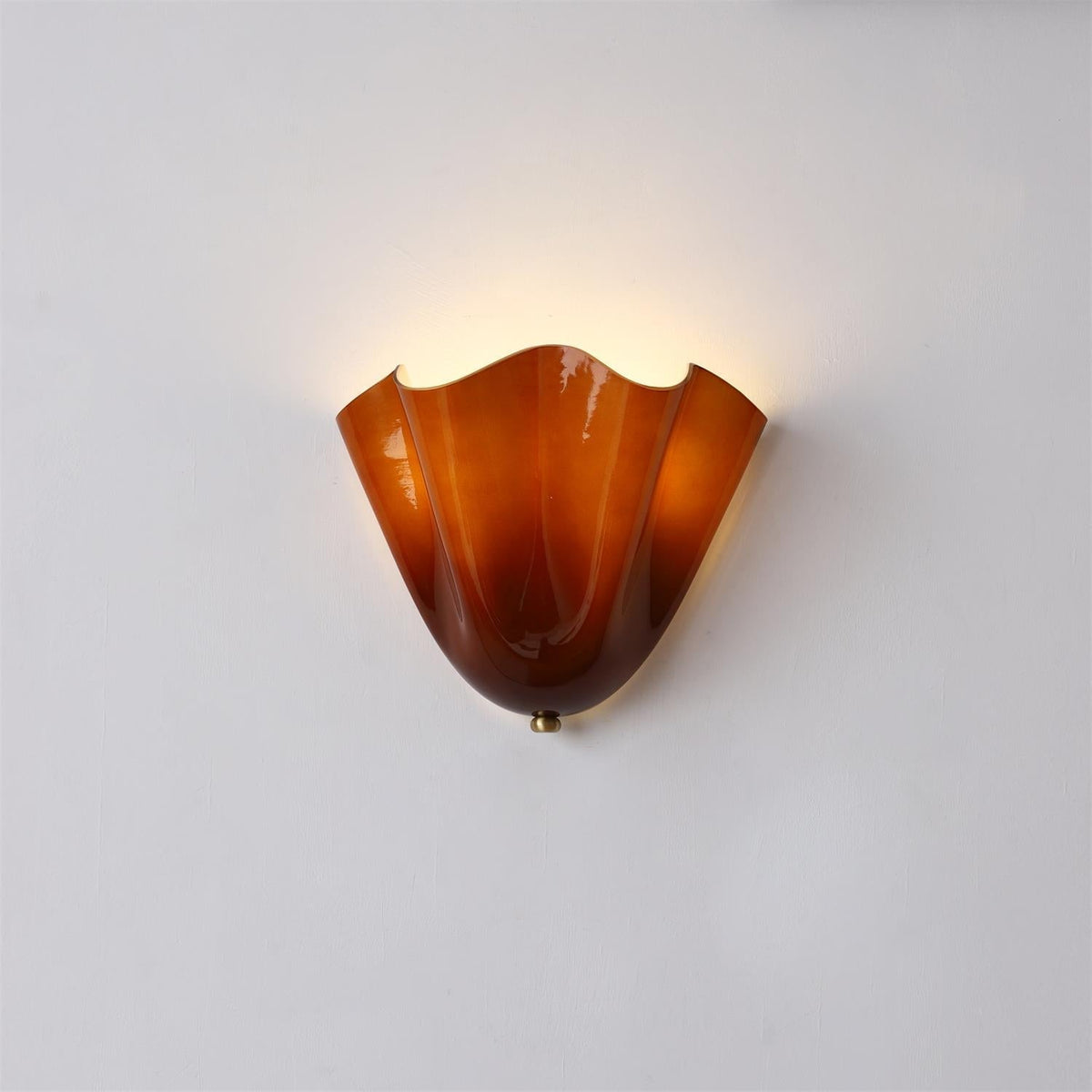 Sefta amber glass wall light lit on a pale wall, showing the honey tone near the rim and the deeper russet at the base