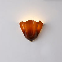Sefta amber glass wall light lit on a pale wall, showing the honey tone near the rim and the deeper russet at the base