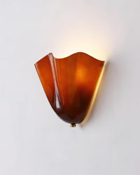 Front view of the lit Sefta amber wall light with light washing up the wall above the open top