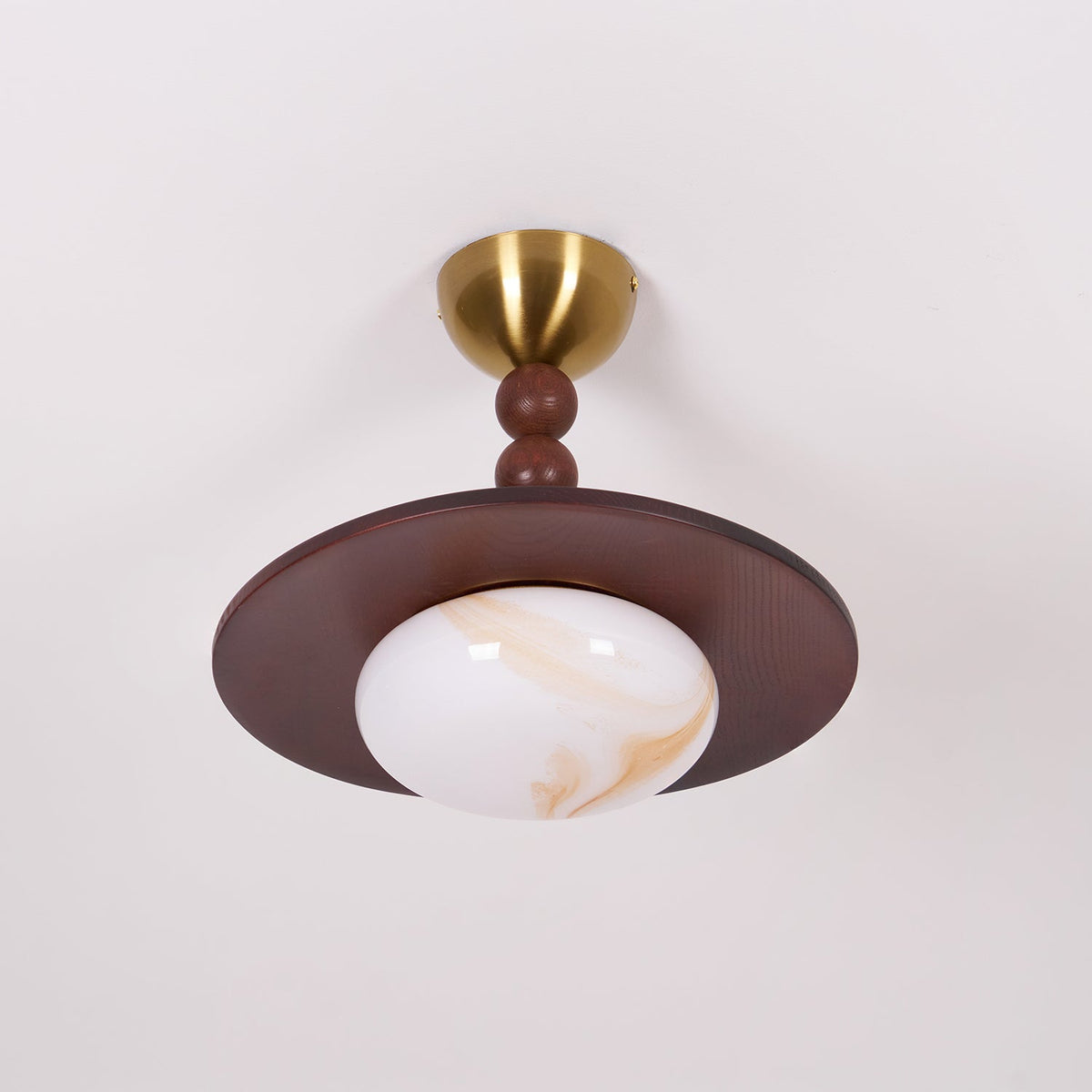 Walo Walnut Alabaster Effect Ceiling Light lit against a pale ceiling showing the brass canopy and bead stack