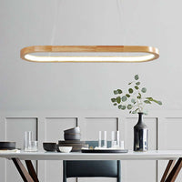 Veona oval wood pendant light lit above a dining table set with dark ceramic bowls and glassware