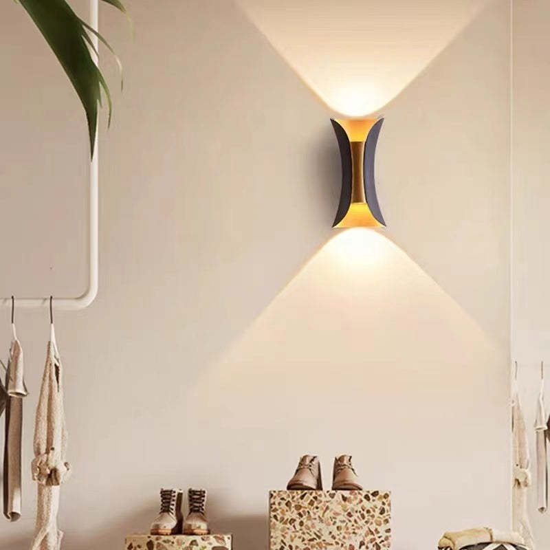 Corva wall light mounted indoors above a boot bench and coat rail, lighting the wall above and below
