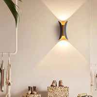 Corva wall light mounted indoors above a boot bench and coat rail, lighting the wall above and below