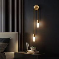 Vano gold wall sconce lit in modern dark bedroom