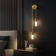 Vano gold wall sconce lit in modern dark bedroom
