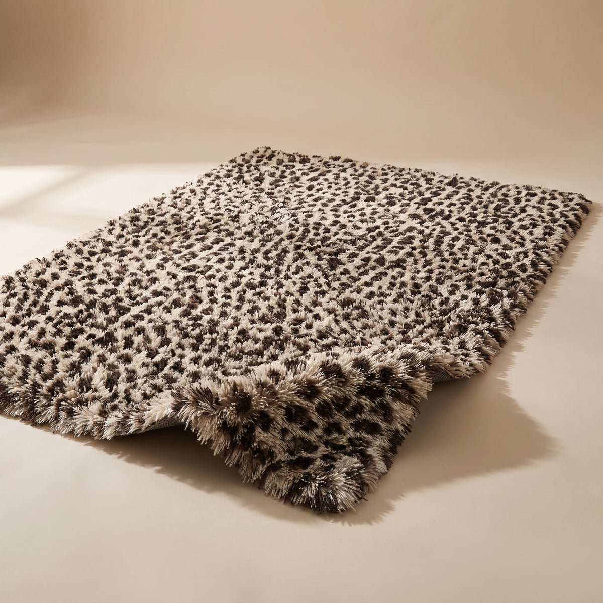 Fauna Shag Rug in the leopard colourway laid flat on a warm plaster studio sweep, one corner lifted to show the long shag pile