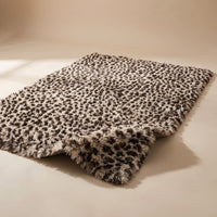 Fauna Shag Rug in the leopard colourway laid flat on a warm plaster studio sweep, one corner lifted to show the long shag pile
