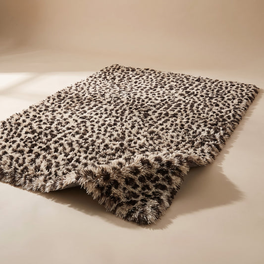 Fauna Shag Rug in the leopard colourway laid flat on a warm plaster studio sweep, one corner lifted to show the long shag pile