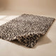 Fauna Shag Rug in the leopard colourway laid flat on a warm plaster studio sweep, one corner lifted to show the long shag pile