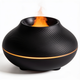 Matte black volcano flame diffuser with swirl-ribbed body, glowing amber base ring and orange flame effect, on a white background