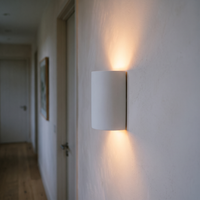 Cova plaster wall light mounted in a hallway at dusk, warm light washing up and down the wall
