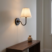 Nora matte black wall light mounted above a narrow wooden console in a hallway