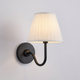 Nora pleated shade wall light with matte black swan-neck arm and white fabric shade on a plain background