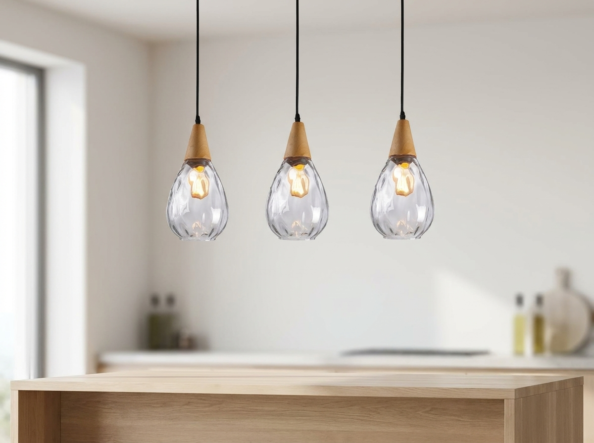 Three Drova clear glass teardrop pendant lights hanging in a row above a pale oak kitchen island