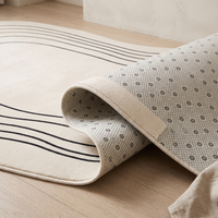 Corner of the Ovala rug folded back to reveal the pale anti-slip backing printed with a dense grid of dots and small florets