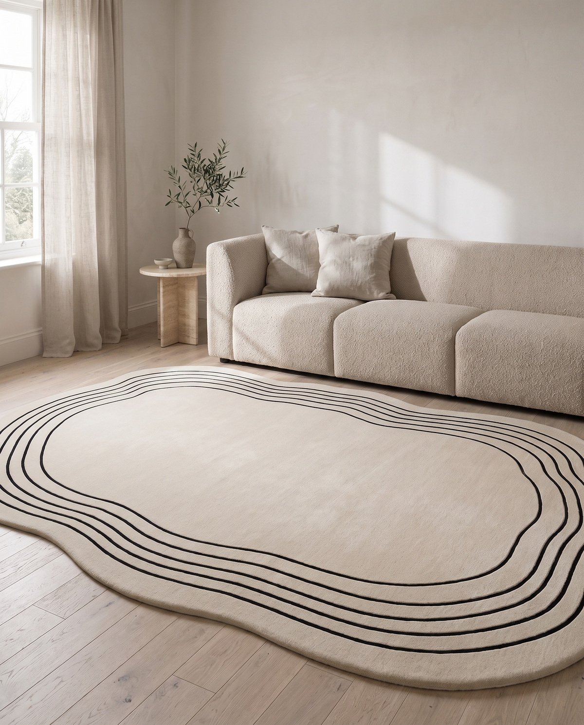 Ovala cream oval rug in a warm neutral living room with a boucle sofa, travertine side table and pale oak floorboards