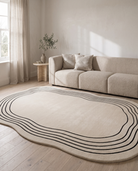 Ovala cream oval rug in a warm neutral living room with a boucle sofa, travertine side table and pale oak floorboards
