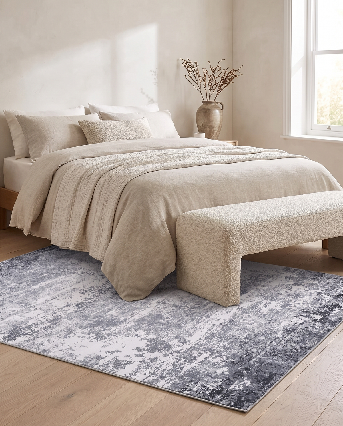 Marlo rug laid at the foot of a linen-dressed bed with a boucle bench in a pale oak bedroom