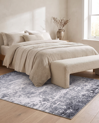 Marlo rug laid at the foot of a linen-dressed bed with a boucle bench in a pale oak bedroom