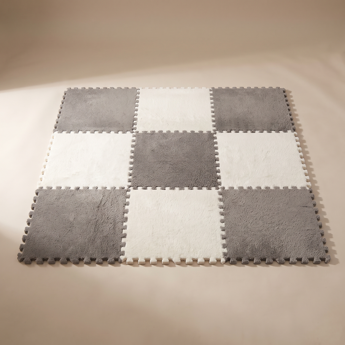 Tessa modular plush rug tiles assembled into a nine-tile checkerboard square in warm ivory and mid grey, jigsaw teeth visible around the edge