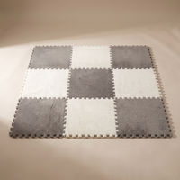Tessa modular plush rug tiles assembled into a nine-tile checkerboard square in warm ivory and mid grey, jigsaw teeth visible around the edge