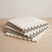 A low flat stack of individual Tessa tiles showing the plush top surface, the lightweight foam core and the interlocking teeth along each thin edge