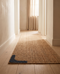Jute runner held flat in a hallway with a Gripo rug gripper fitted at the corner