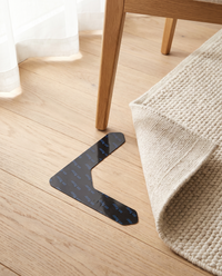 Gripo rug gripper on oak flooring beside a chair leg and rug corner showing its real size