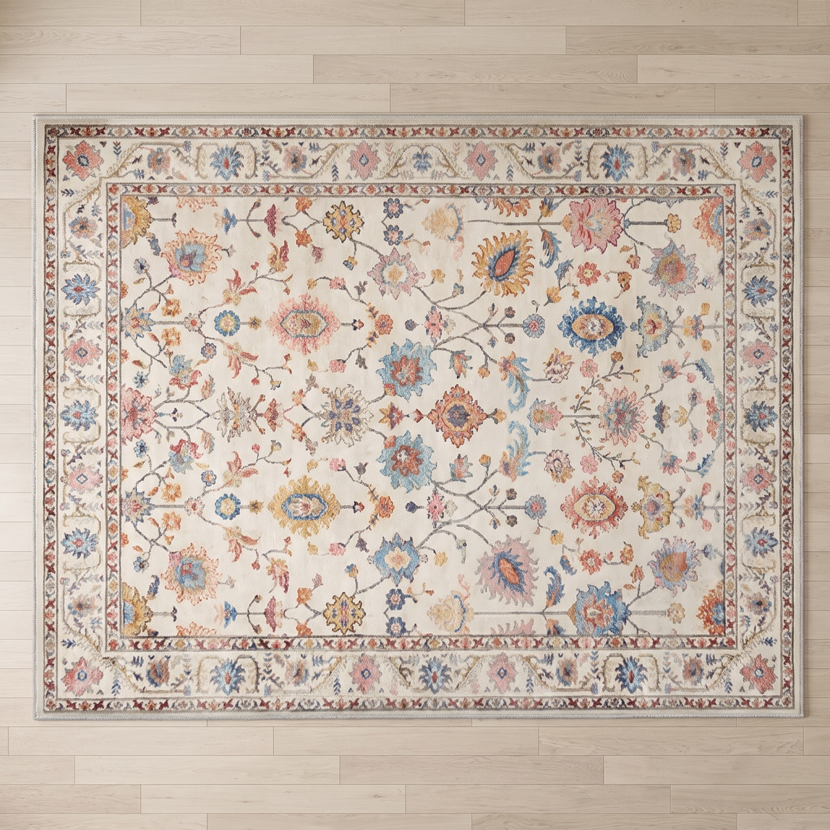 Overhead view of the full Bahia rug on pale oak boards, showing the complete botanical field and cornered multi-band border