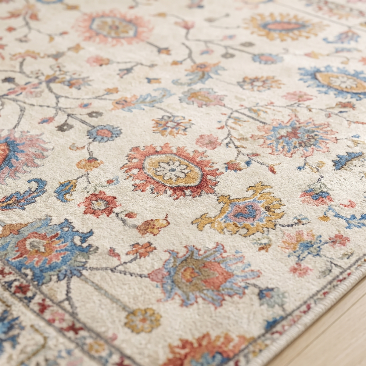 Close-up of the Bahia rug's short dense crystal velvet pile, showing the printed coral, powder blue and ochre floral detail in raking daylight