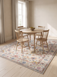 Bahia rug set beneath a round oak dining table and four wooden chairs in a bright plaster walled dining room