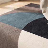 Macro close-up of the Lindo rug's low dense flannel pile where the petrol teal circle meets charcoal and off-white over warm taupe