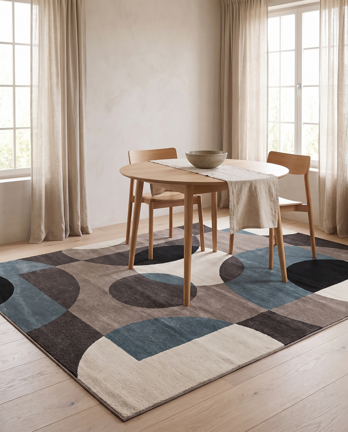 Lindo rug beneath a round oak dining table and chairs in a light UK dining nook with linen curtains