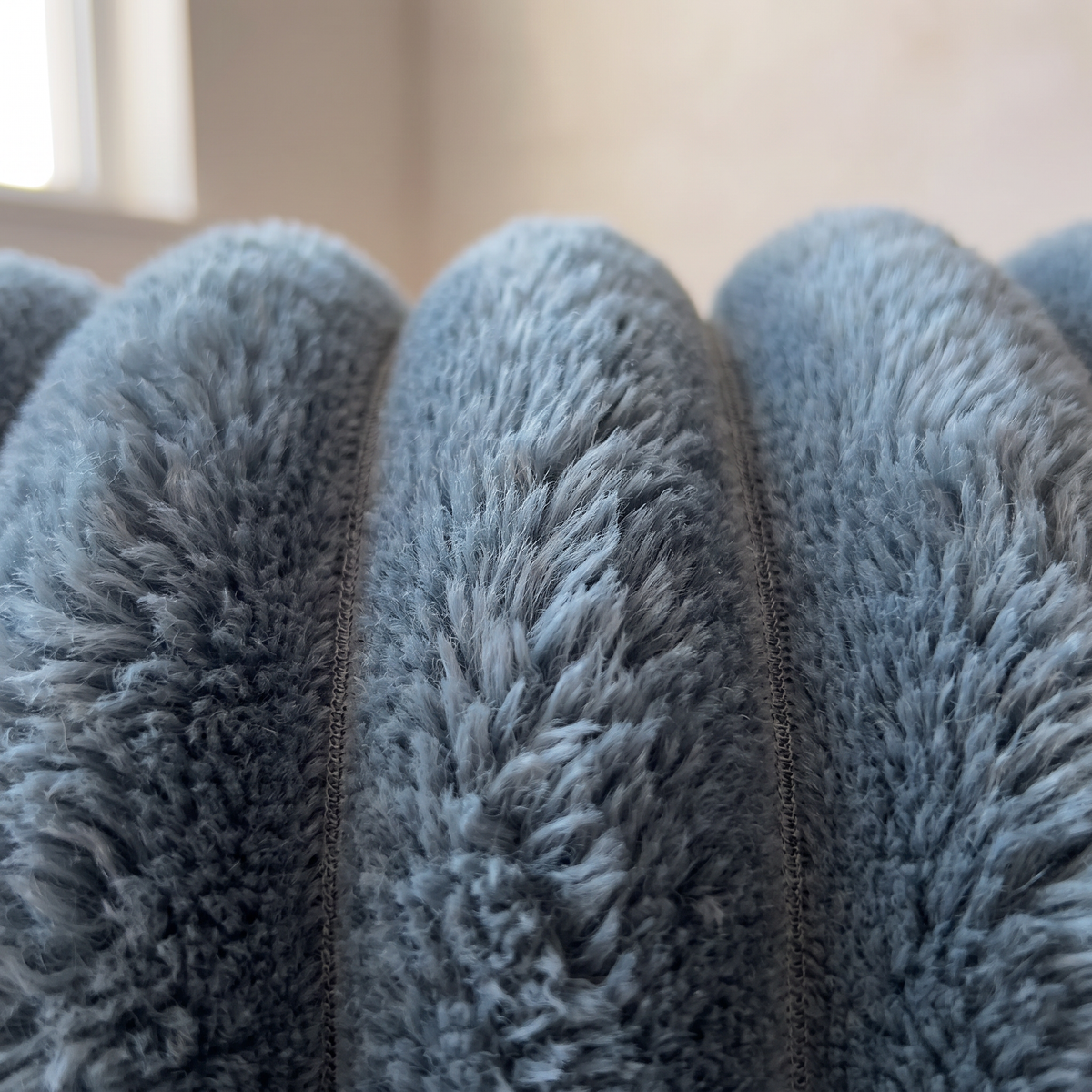 Close-up of the Nordo throw blanket's coral fleece pile, showing the depth of the fibres and the fine stitched seam between each raised rib