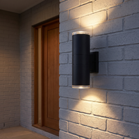 Belvo twin-head wall light on a grey brick porch wall beside a timber front door at night