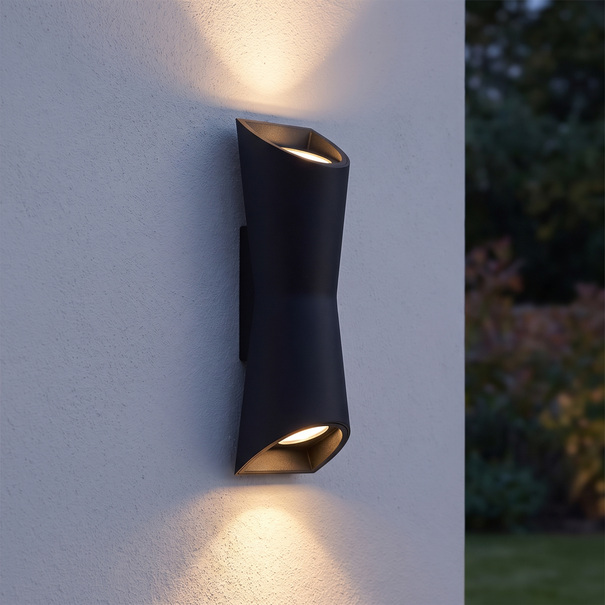 Kestro Torch wall light mounted on a pale rendered garden wall at dusk with warm light cones above and below