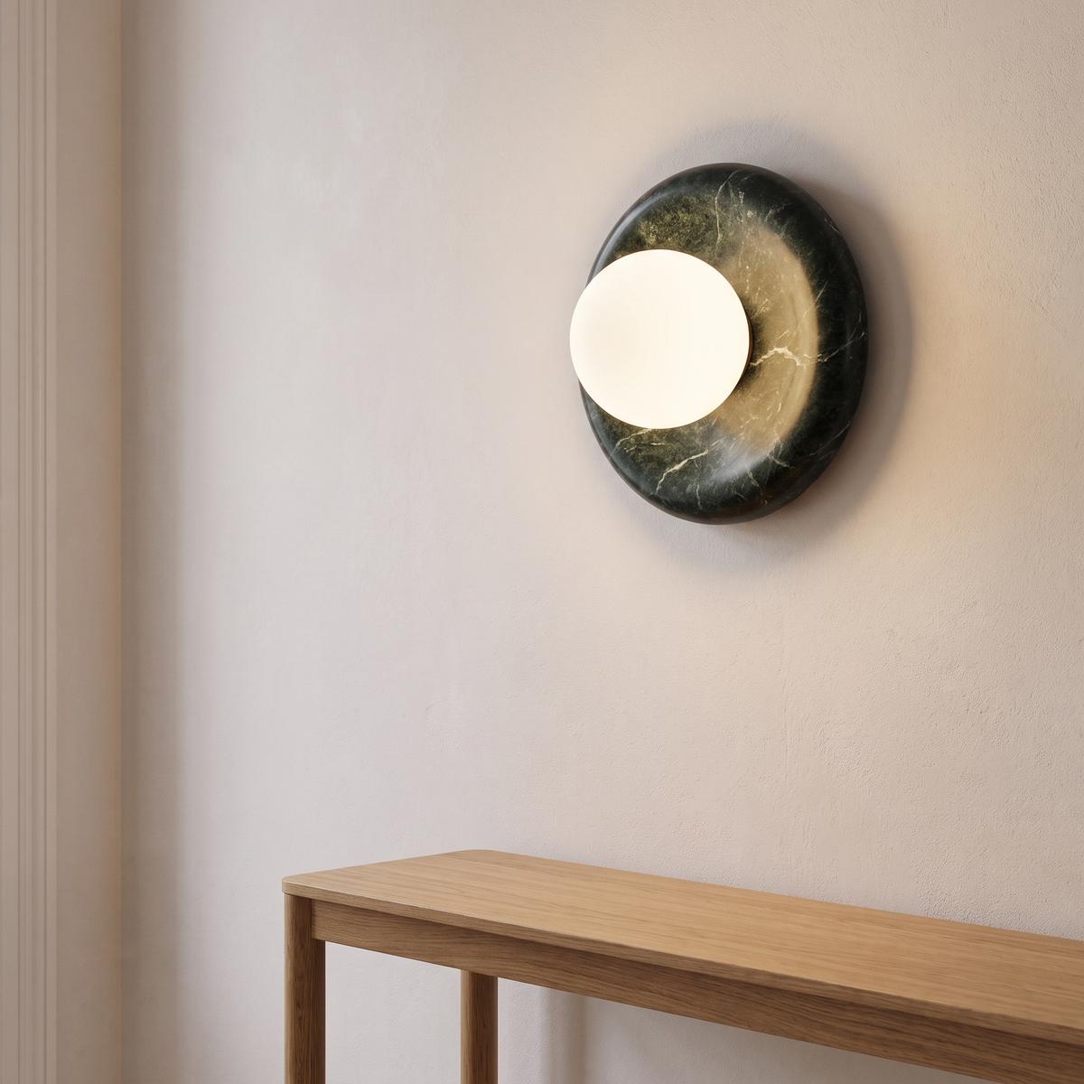 Avilo green marble sconce lit above an oak console table in a hallway