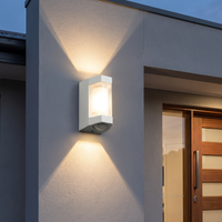 White Marvo Up-Down Outdoor Wall Light beside a front door at dusk, casting warm beams up and down the wall